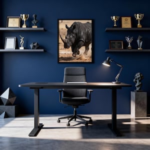 Peut inclure: Un bureau moderne avec un mur bleu foncé, un bureau noir et une chaise de bureau noire. Une photo encadrée en noir et blanc d'un rhinocéros est accrochée au mur. Des étagères présentent des trophées et des objets décoratifs. Une lampe de bureau noire éclaire le bureau.