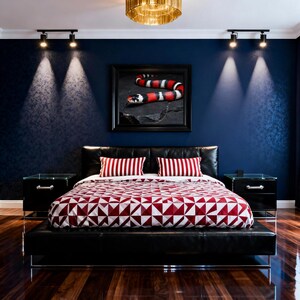 Peut inclure: Chambre moderne avec lit en cuir noir et tables de chevet assorties. La literie présente un motif géométrique rouge et blanc, complété par des oreillers rayés. Une œuvre d'art encadrée d'un serpent est accrochée au-dessus du lit, sur un mur bleu foncé.