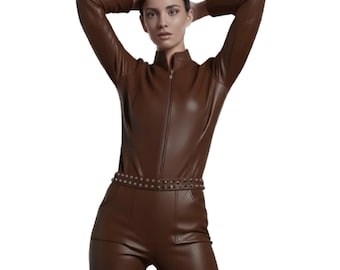 May include: A brown leather jumpsuit with a high collar and a front zipper. The jumpsuit features long sleeves and a studded belt around the waist. The model is wearing the jumpsuit with their arms raised above their head.