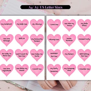 Può includere: Due fogli di adesivi rosa a forma di cuore con frasi come "Ti amo" e "Sei la mia casa". Gli adesivi sono disposti su uno sfondo bianco, con il testo "A4/A5/US Letter Sizes" in alto. Ideali per il crafting o lo scrapbooking.