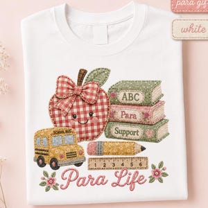 White Para Life T-shirt featuring a patchwork apple, school bus, stacked books labeled ABC, Para and Support, pencil, ruler, flowers, and pink Para Life lettering.