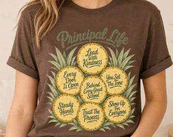 Könnte beinhalten: Ein dunkelbraunes Kurzarm-T-Shirt mit einer Ananas-Grafik und dem Text Principal Life, Lead With Kindness, Every Door Is Open, Behind Every Great School, You Set The Tone, Steady Hands, Trust The Process, Show Up For Everyone.