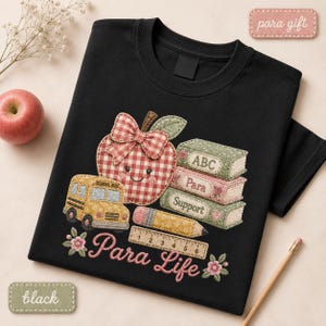 Black  Para Life T-shirt featuring a patchwork apple, school bus, stacked books labeled ABC, Para and Support, pencil, ruler, flowers, and pink Para Life lettering.