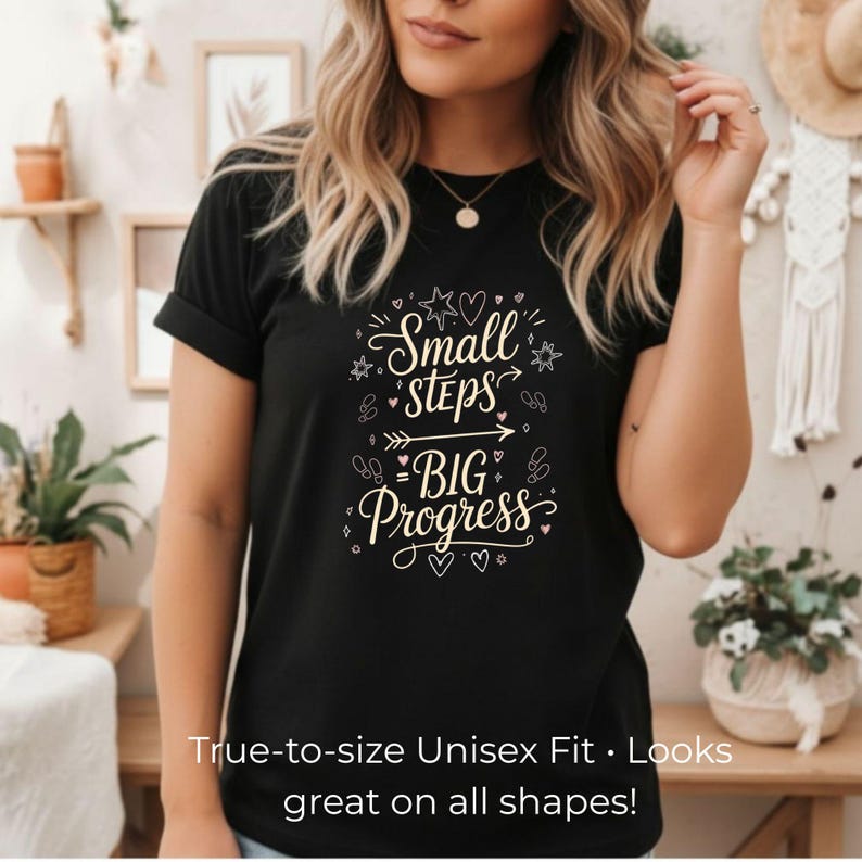 May include: Black t-shirt with the text "Small Steps = BIG Progress" in a decorative font. The shirt also has the text "True-to-size Unisex Fit. Looks great on all shapes!"