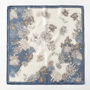 May include: A square silk scarf with a floral pattern. The scarf has a cream-coloured centre with brown and grey flowers. The border is a solid blue with a white inner border.