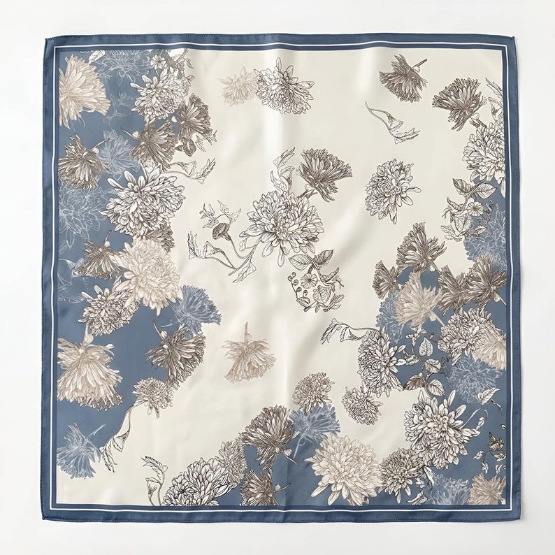 May include: A square silk scarf with a floral pattern. The scarf has a cream-coloured centre with brown and grey flowers. The border is a solid blue with a white inner border.