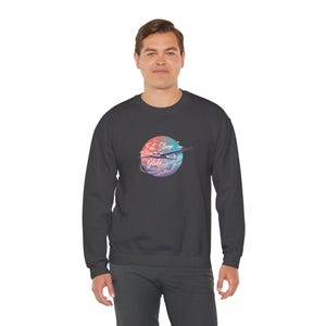 May include: Dark grey sweatshirt with a colourful graphic. The graphic features a stylized aeroplane and the words "Eat, Sleep, Glide" in a cursive font, set against a backdrop of pastel clouds. The sweatshirt is a crew neck style.