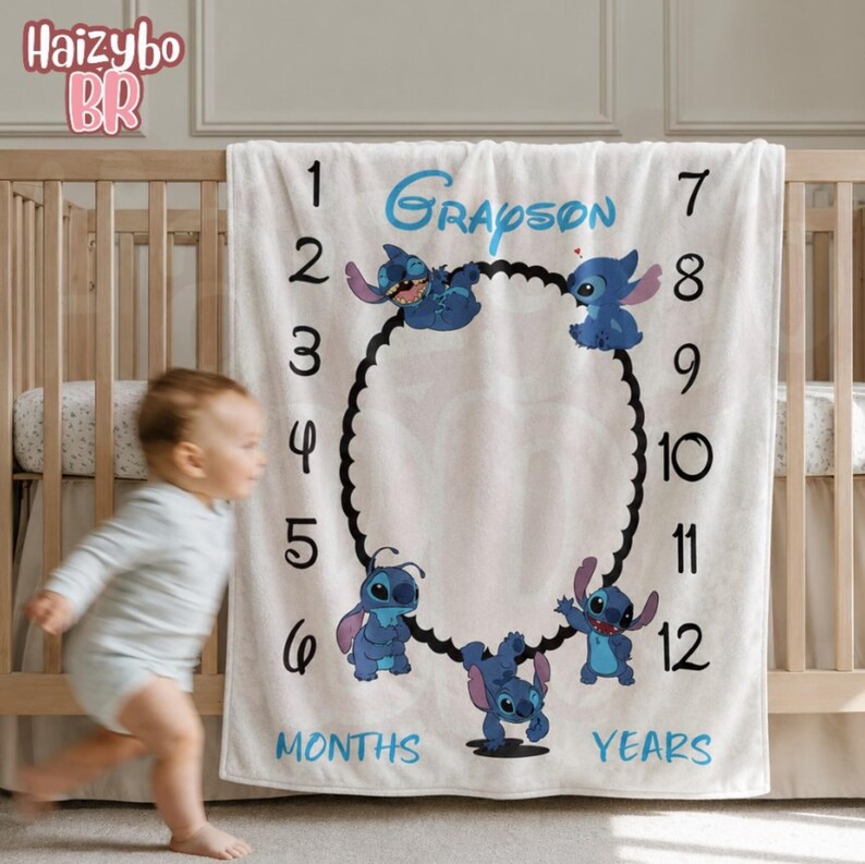 May include: A white milestone blanket featuring the name Grayson in blue script, surrounded by numbers 1 through 12 and the words MONTHS and YEARS. The blanket displays four blue Stitch characters arranged around a central black scalloped oval frame.