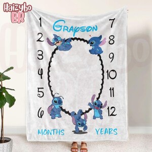 May include: A white milestone blanket featuring the name Grayson in blue text, surrounded by numbers 1 through 12, the words MONTHS and YEARS, and four blue Stitch characters arranged around a central black scalloped oval frame.