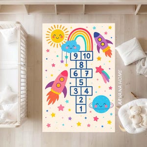 May include: A colorful hopscotch rug featuring a playful design with a sun, rainbow, rockets, planets, and stars. The numbers 1 through 10 are displayed in a hopscotch grid. The rug is designed for children's play areas.