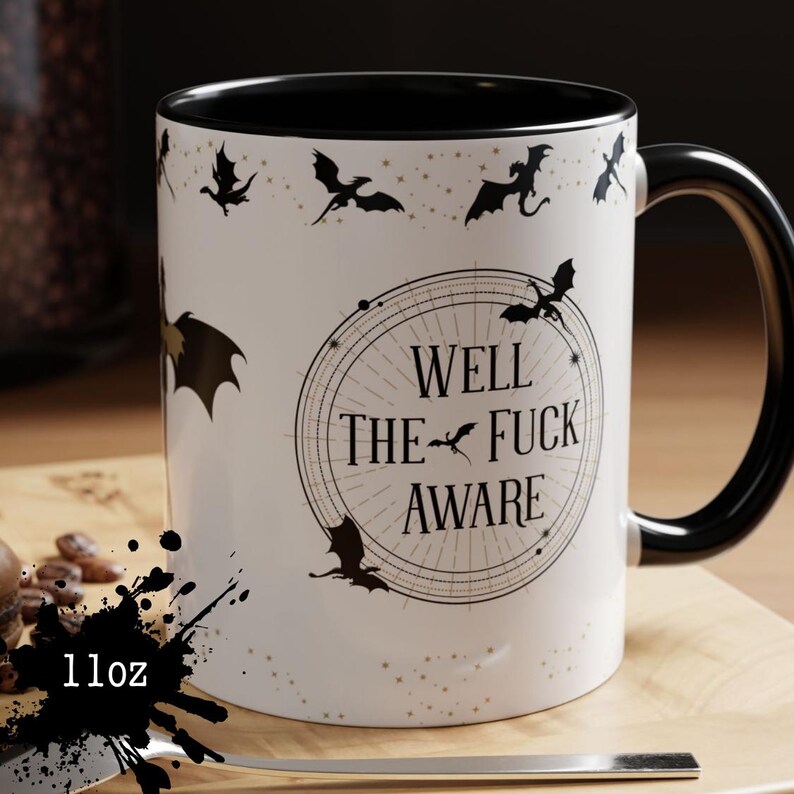 May include: White ceramic mug with a black interior and handle. The mug features a design of black dragons and the text "WELL THE FUCK AWARE" in a circular design. The mug is 11oz.