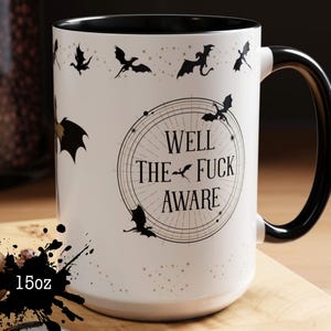 May include: A white ceramic mug with a black handle and rim. The mug features a design of black bats and the text "WELL THE FUCK AWARE" in a circular design. The mug holds 15oz.