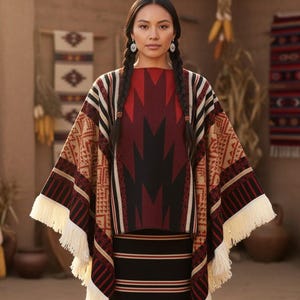Könnte beinhalten: Eine Frau in traditioneller indianischer Kleidung. Das Ensemble umfasst einen gemusterten Poncho mit Fransen, ein passendes Oberteil und einen gestreiften Rock. Die Farbpalette umfasst Rot, Schwarz, Beige und Weiß.