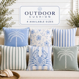 May include: Six square outdoor cushions featuring blue and white patterns including palm trees, floral motifs, vertical stripes, and a crab illustration. A sign above reads OUTDOOR CUSHION 4 AVAILABLE SIZES with a seashell icon.
