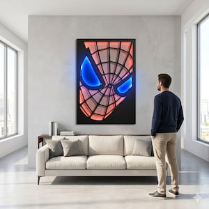 May include: A rectangular wall art piece featuring a stylized, layered mask design with a black webbed pattern over a glowing red background and two prominent, bright blue, almond-shaped eye cutouts, mounted on a light gray wall.