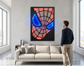 May include: A rectangular wall art piece featuring a stylised, layered mask design with a black webbed pattern over a glowing red background and two prominent, bright blue, almond-shaped eye cutouts, mounted on a light grey wall.