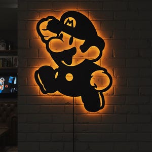 K&ouml;nnte beinhalten: Schwarze Silhouette einer springenden Videospiel-Figur mit orangefarbener Beleuchtung. Die Figur ist an einer Ziegelmauer befestigt. Die Figur tr&auml;gt einen Hut mit einem "M" darauf.