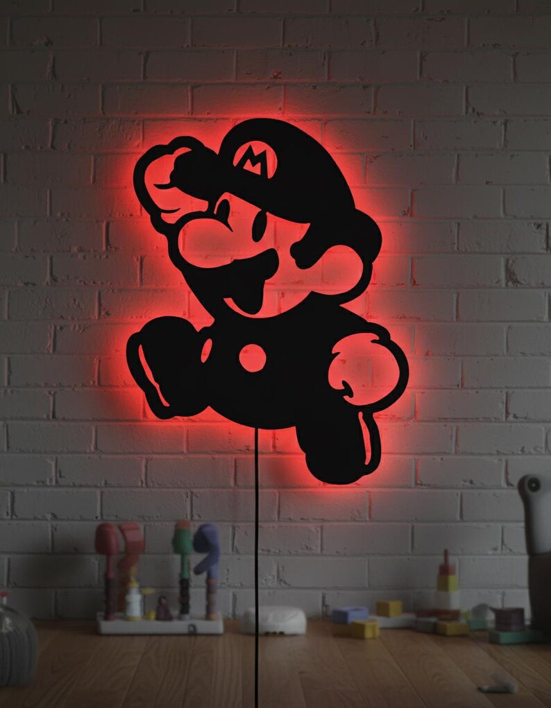 K&ouml;nnte beinhalten: Schwarze Silhouette der Videospiel-Figur Mario, mit rotem Neonlicht, das die Figur umrandet. Das Kunstwerk ist an einer wei&szlig;en Backsteinmauer angebracht. Ein schwarzes Netzkabel erstreckt sich von der Unterseite des Kunstwerks.