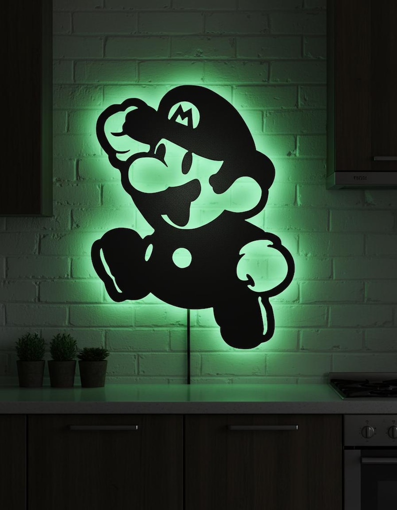 K&ouml;nnte beinhalten: Schwarze Silhouette der Videospiel-Figur Mario in Laufpose, beleuchtet von gr&uuml;nen LED-Lichtern. Das Kunstwerk ist an einer wei&szlig;en Backsteinmauer &uuml;ber einer Arbeitsplatte und Schr&auml;nken angebracht. Ein lustiges, dekoratives St&uuml;ck.