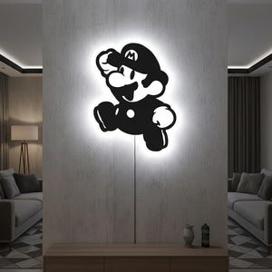 K&ouml;nnte beinhalten: Schwarz-wei&szlig;e Wandkunst des Videospielcharakters Mario in einer Laufpose. Das Kunstwerk wird von einem wei&szlig;en Licht beleuchtet, wodurch eine leuchtende Kontur entsteht. Die Kunst ist an einer grauen Wand angebracht.