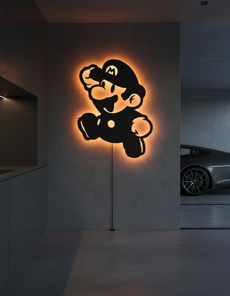 K&ouml;nnte beinhalten: Schwarze Silhouette der Videospiel-Figur Mario, beleuchtet mit einem orangefarbenen Schein. Die Wandkunst ist an einer grauen Wand angebracht. Die Figur befindet sich in einer Laufpose, mit schwarzem Hut und Latzhose.
