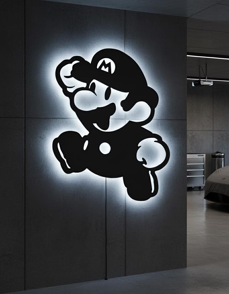 K&ouml;nnte beinhalten: Schwarz-wei&szlig;e, beleuchtete Wandkunst mit einer Silhouette der Videospiel-Figur Mario in einer Sprungpose. Das Kunstwerk ist an einer grauen Wand angebracht und strahlt ein sanftes, wei&szlig;es Leuchten um die Konturen der Figur aus.