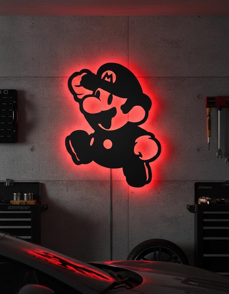 K&ouml;nnte beinhalten: Schwarze Silhouette der Videospiel-Figur Mario, mit roter Neonbeleuchtung. Das Kunstwerk ist an einer Betonwand befestigt und erzeugt einen auff&auml;lligen Kontrast. Das Bild zeigt einen springenden Mario.
