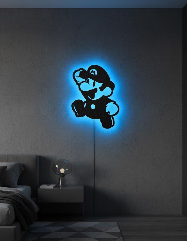 K&ouml;nnte beinhalten: Schwarze Silhouette der Videospiel-Figur Mario in Laufpose, mit blauem Neonlicht, das die Figur umrandet. Die Wandkunst ist an einer grauen Wand angebracht, mit einem Netzkabel sichtbar.
