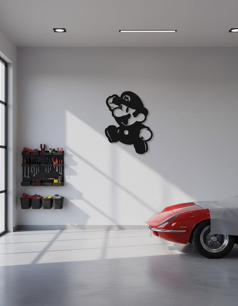 K&ouml;nnte beinhalten: Schwarze Metall-Wandkunst des Videospielcharakters Mario in einer Laufpose. Das Kunstwerk ist an einer wei&szlig;en Wand in einer Garage angebracht. Ein roter Sportwagen ist teilweise im Hintergrund zu sehen.