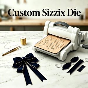 Könnte beinhalten: Eine weiße Sizzix Big Shot Stanzmaschine mit einem Holzstanzwerkzeug mit Schleifenformen. Eine marineblaue Schleife mit goldenem Besatz liegt neben der Maschine. Der Text "Custom Sizzix Die" steht oben.
