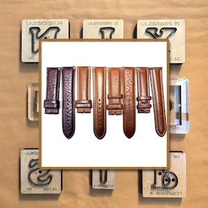 Pode incluir: Uma coleção de pulseiras de relógio de couro castanho em várias tonalidades, do bordô escuro ao castanho claro, exibidas sobre um fundo neutro. As pulseiras têm diferentes estilos de fivelas e detalhes de costura. Blocos de madeira com texto no fundo.