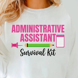 May include: White sweatshirt featuring the text "ADMINISTRATIVE ASSISTANT SURVIVAL KIT" in pink and black. The design includes a pink push pin, a green and yellow pencil, and a pink notepad.