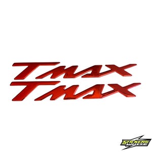 Può includere: Due serie di decalcomanie rosse lucide "TMAX", ciascuna con le lettere disposte orizzontalmente. Le decalcomanie sono su sfondo bianco. Il logo "STICKERS WHITE" si trova in basso a destra.