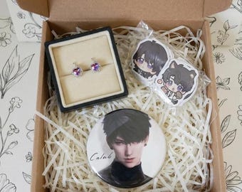 May include: A cardboard gift box filled with shredded paper containing a pair of heart-shaped stud earrings in a black display box, two small anime-style character stickers, and a circular pinback button featuring a portrait of a person with dark hair and the text Calab.