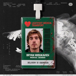 May include: A rectangular green identification badge featuring a red heart-shaped logo, the text LIGHTFOOT MEDICAL TRANSPORT, a photograph of a person, a barcode, and the name BRYAN HODUKAVICH, MEDICAL COURIER, with red blood-like splatters.