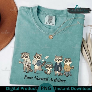 Puede incluir: Una camiseta de cuello redondo color verde azulado con un gráfico de cinco mapaches realizando diversas tareas y el texto "Para Normal Activities" impreso debajo. La prenda incluye una etiqueta Comfort Colors y un collar de tono plateado.