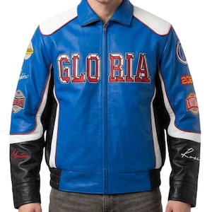 Puede incluir: Chaqueta de cuero azul con detalles en blanco y negro. La chaqueta presenta la palabra "GLORIA" en letras rojas en el pecho. Parches y escritura en las mangas. Tiene cremallera frontal y dobladillo acanalado.