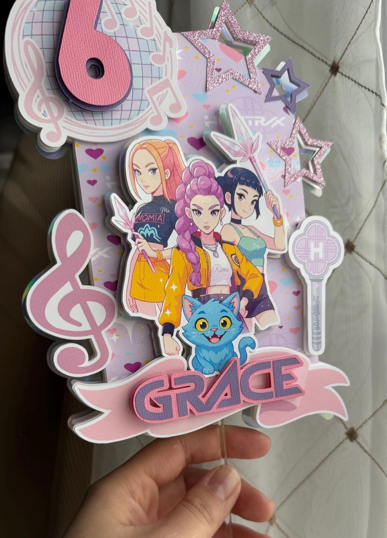 May include: A layered cake topper featuring three anime-style girls, a blue cat, and the name "GRACE" on a pink banner. The design includes musical notes, stars, and a large number six.