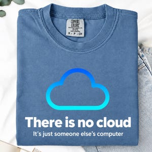 以下が含まれることがあります： 青いクルーネックTシャツ。青いグラデーションの雲の輪郭が描かれています。雲の下には「There is no cloud. It's just someone else's computer.」という白い文字がプリントされています。首元にはComfort Colorsのタグが付いています。