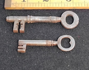 Dos llaves antiguas de alrededor de 1800, una con un corazón en el lazo y una E en la hoja, la otra religiosa o con la figura del hombre verde.