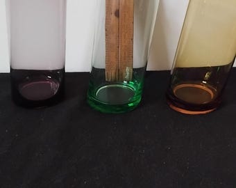 Tres vasos inclinados de colores diferentes, soplados a mano y en perfecto estado.