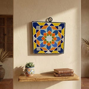 Peut inclure: Une décoration murale carrée présentant un motif géométrique en mosaïque bleu, jaune, orange, bleu clair et gris. L'objet possède un cadre en métal noir avec un anneau de suspension circulaire au sommet, affichant un motif en étoile.