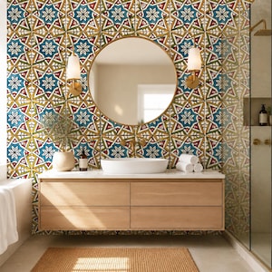 Peut inclure: Un meuble de salle de bain en bois clair à quatre tiroirs, surmonté d'une vasque ovale blanche et d'un miroir rond. Le mur est recouvert de carreaux carrés à motif d'étoiles géométriques bleu, rouge, vert et jaune, encadrés par deux appliques.