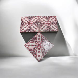 Puede incluir: Tres azulejos cuadrados de cerámica dispuestos en formación triangular. Cada azulejo presenta un fondo blanco con un patrón floral y geométrico de color rosa oscuro que consiste en líneas curvas y pequeños motivos de pétalos.
