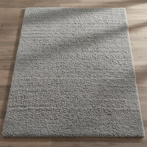 Mustard hand-tufted shag rug in a modern living room; soft yellow solid-color wool rug on light wood floor.