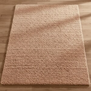 Mustard hand-tufted shag rug in a modern living room; soft yellow solid-color wool rug on light wood floor.