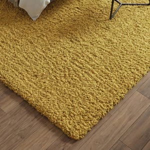 Mustard hand-tufted shag rug in a modern living room; soft yellow solid-color wool rug on light wood floor.