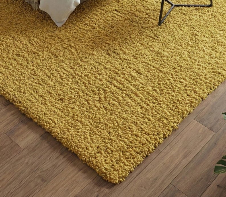 Mustard hand-tufted shag rug in a modern living room; soft yellow solid-color wool rug on light wood floor.