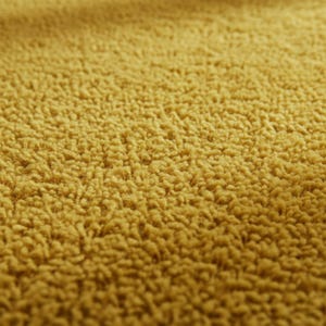 Mustard hand-tufted shag rug in a modern living room; soft yellow solid-color wool rug on light wood floor.