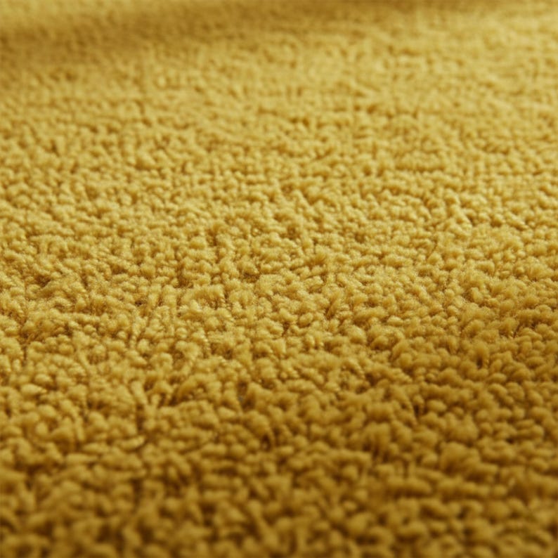 Mustard hand-tufted shag rug in a modern living room; soft yellow solid-color wool rug on light wood floor.